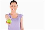 Gorgeous woman holding an apple while standing against a white background