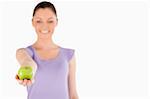 Pretty woman holding an apple while standing against a white background