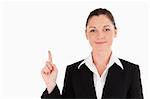 Good looking woman in suit pointing at a copy space while standing against a white background