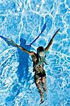 Young active woman swimming under water in the pool during one splendid day of summer full of sun