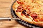 A slice of pizza is lifted from the pan with a spatula