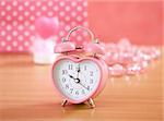 pink clock on wooden table