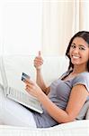 woman on sofa working with notebook with thumb up in livingroom