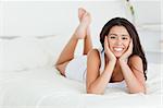 goodlooking woman lying on bed with crossed legs looking into camera in bedroom