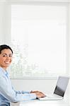 Beautiful woman working with her laptop and posing while sitting at the office