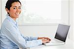 Good looking woman working with her laptop and posing while sitting at the office