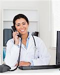 Good looking woman doctor on the phone while sitting in her office