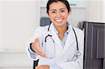 Beautiful female doctor inviting somebody to seat while looking at the camera in her office