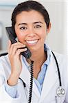 Pretty female doctor on the phone and posing in her office