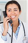 Beautiful female doctor on the phone and posing in her office