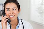 Attractive female doctor on the phone and posing in her office