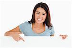 Portrait of a gorgeous woman pointing at a board while standing against a white background