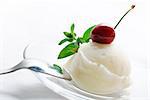 Vanilla ice cream decorated with fresh mint and cherry