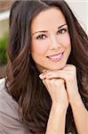 Portrait of a beautiful brunette young woman with perfect teeth smiling and resting on her hands