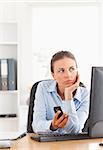 Portrait of a working woman with her cellphone in her office