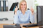 Young woman sitting behind desk with thumbs up in an office
