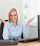 Smiling woman sitting behind desk not having a clue what to do next inan office