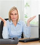 Serious woman sitting behind desk not having a clue what to do next in an office