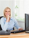 Working smiling woman in front of a screen looking into camera in an office