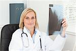 Charming doctor holding x-ray looks into camera in her office