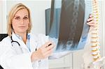 Serious doctor looking at x-ray looks into camera in her office