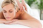 Close up of a smiling woman relaxing with eyes closed on a lounger during a massage in a wellness center