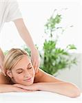 Close up of a blonde woman relaxing on a lounger enjoys a massage in a wellness center