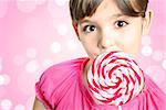 Beautiful little girl with lollipop in front of the pink background