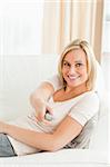 Portrait of a woman pointing a remote at the camera in the living room