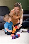 Young mother playing with baby boy ( 1 year old ) at home.