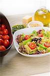 fresh healthy homemade italian fusilli pasta salad with parmesan cheese,pachino cherry tomatoes, black olives and mix vegetables ,dressed with extra-virgin olive oil and pesto sauce