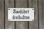 Metal sign Ausfahrt freihalten on a wooden gate