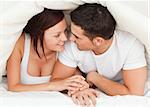 Couple hiding under a blanket in the bedroom