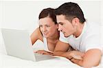 Cheerful couple with a laptop in the bedroom