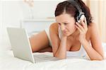 Woman listening to music working on a laptop in the bedroom