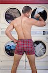 Partially dressed man in Laundromat checks the time