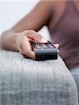 closeup of woman on sofa, changing tv channel with remote control. Front view, copy space