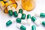 Pill Containers with Green and White capsules inside, all on a bright white background