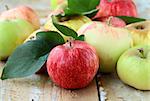 Red,green and yellow apples with leaves on wooden table