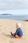 thoughtful toddler sitting alone on the beach