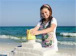 Happy girl building sandcasttle on a beach