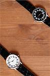 Pair of modern black and white wristwatches on wooden surface