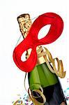 Detail of champagne bottle with red mask, ribbons and confetti