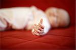 Detail of hand of sleeping baby on red background