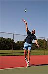 Young man serving tennis ball