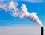 chimney billowing white smoke into blue sky