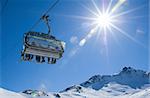 skiers in a chairlift backlit by the sun and spreading sunflares