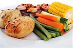 Seasonal fresh vegetables including carrot, beans, corn, zuchini and potatoes on a plate with steak and seafood.