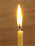 close-up of the burning candle at brown background