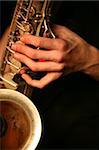 Hands of the saxophonist with a saxophone on a black background